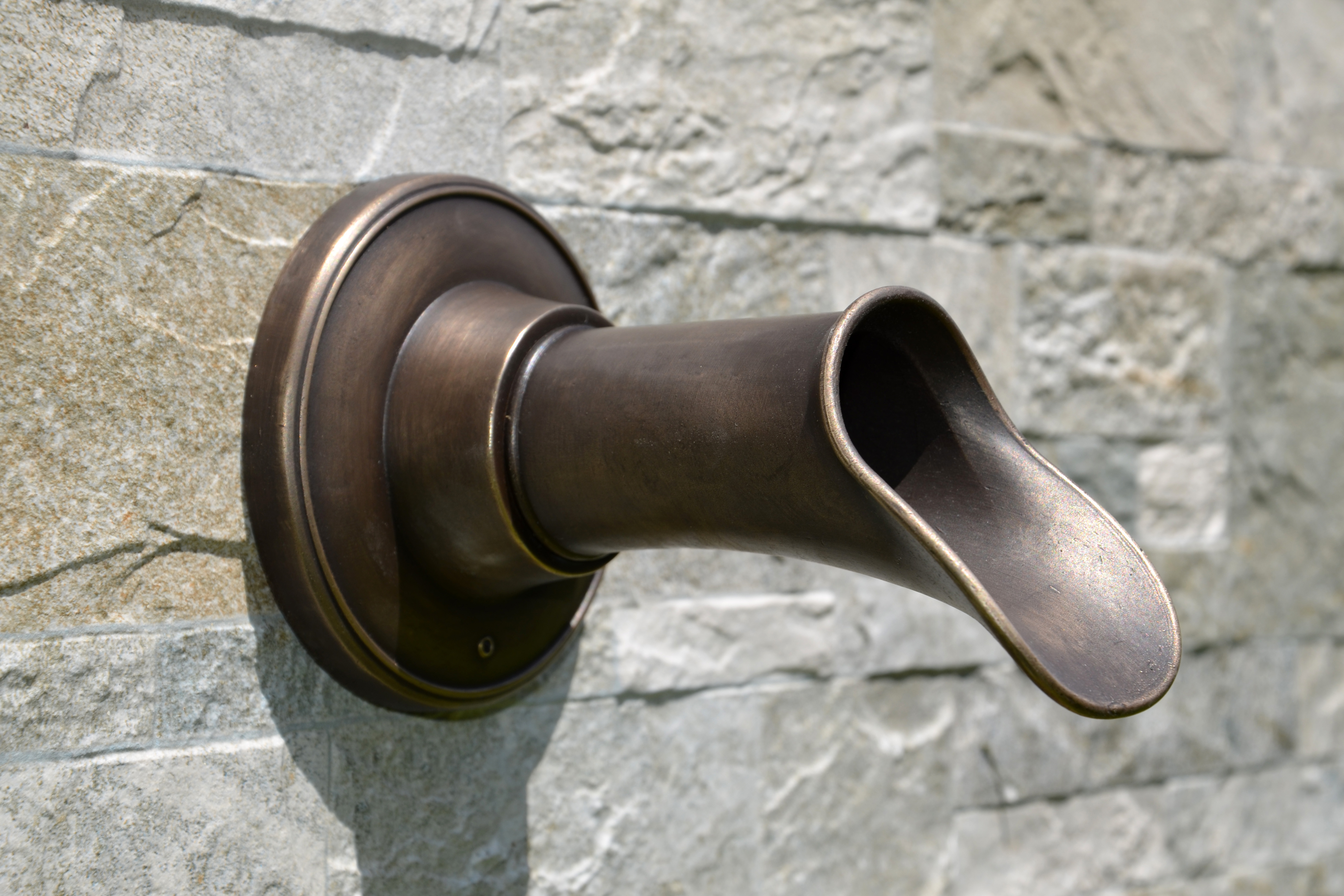 small Oona bronze fountain spout on a stone background
